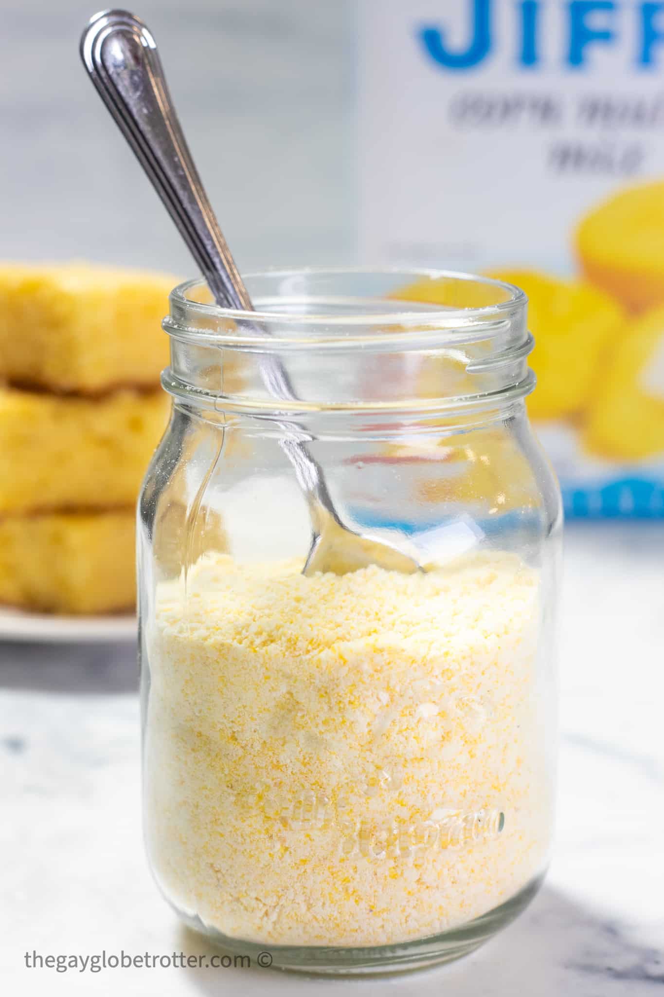 A jar of jiffy corn muffin mix with a spoon and cornbread.