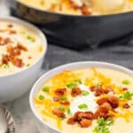 Two bowls of loaded baked potato soup garnished with bacon.