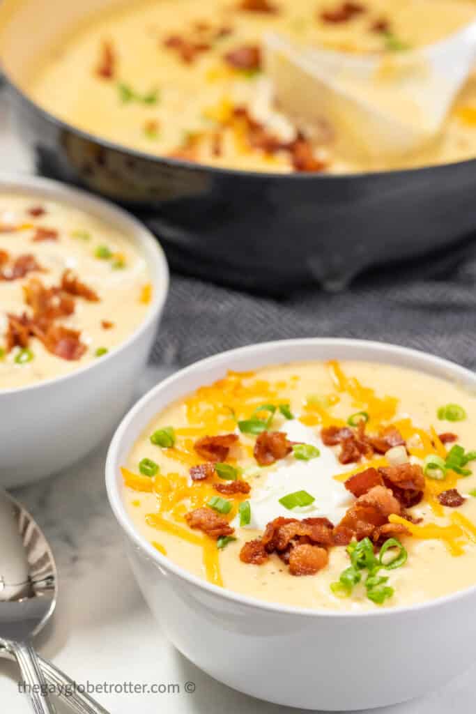 Two bowls of loaded baked potato soup garnished with bacon.