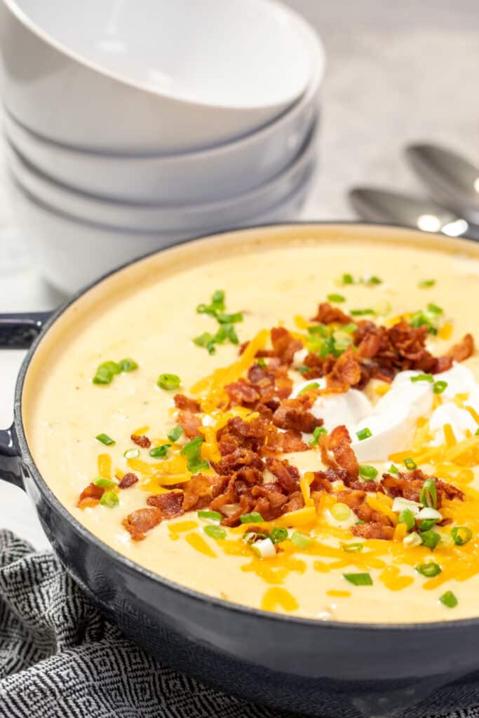 A pot of loaded baked potato soup with toppings.