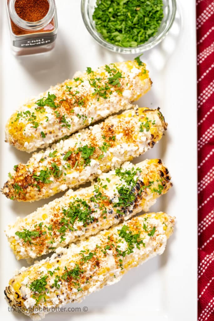 Mexican street corn on a plate with cilantro and chili powder.
