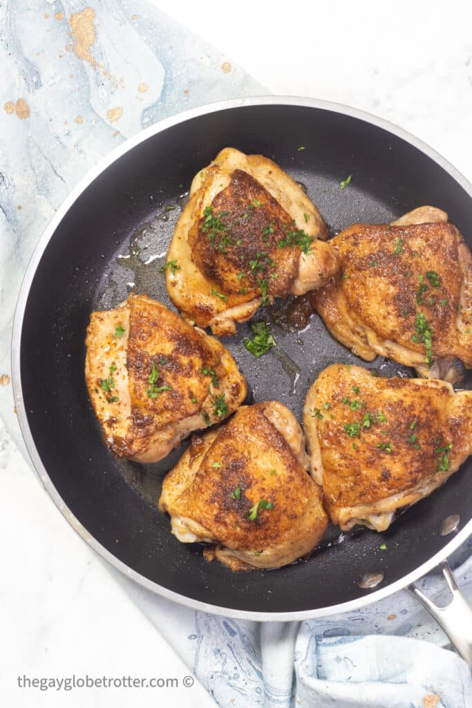 Old bay chicken thighs in a serving pan.