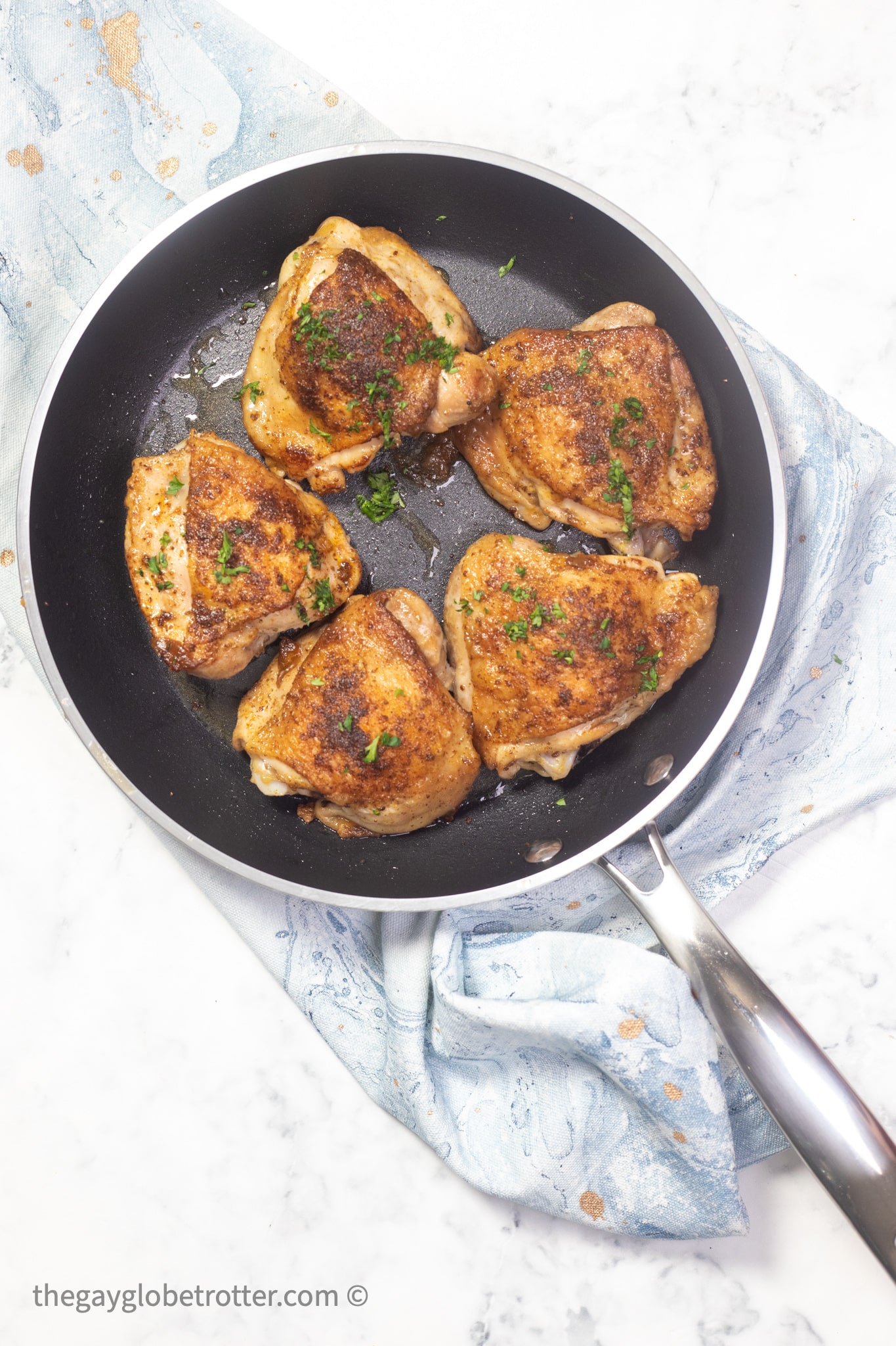 A pan of old bay chicken thighs garnished with parsley.