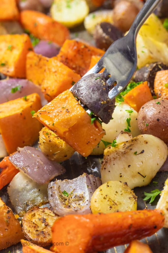 A fork picking up root vegetables from a plate.