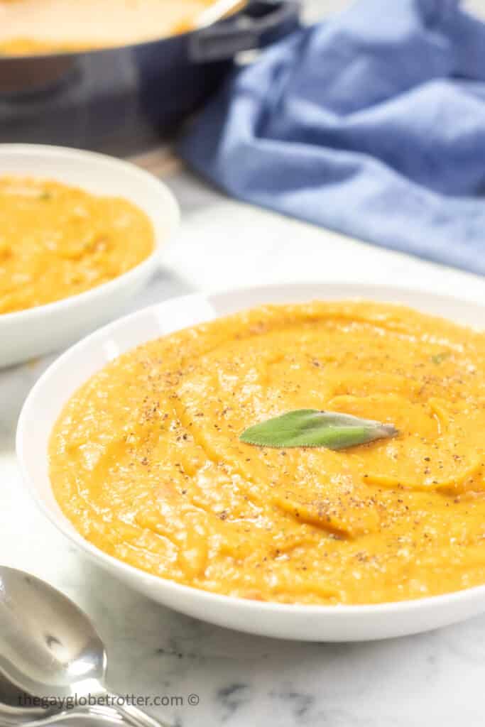 Bowls of roasted root vegetable soup next to some spoons.