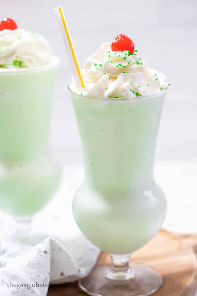 A milkshake with whipped cream and a cherry.