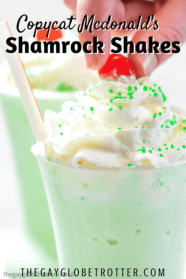 A hand putting a cherry on a shamrock shake.