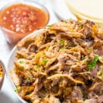 A serving platter of slow cooker pork carnitas with parsley.