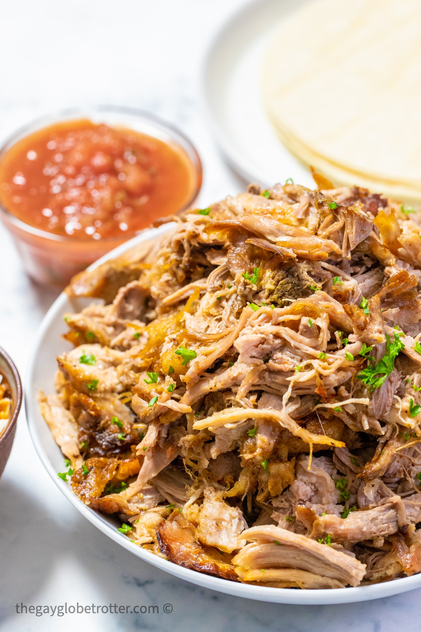 A serving platter of slow cooker pork carnitas with parsley.