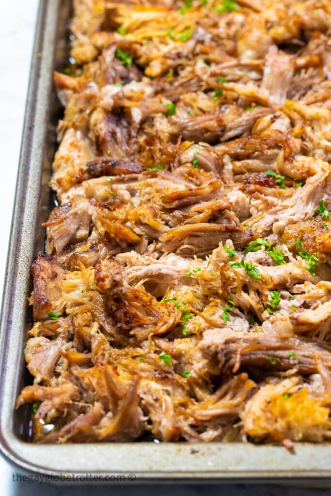 A baking tray of pork carnitas that were broiled.