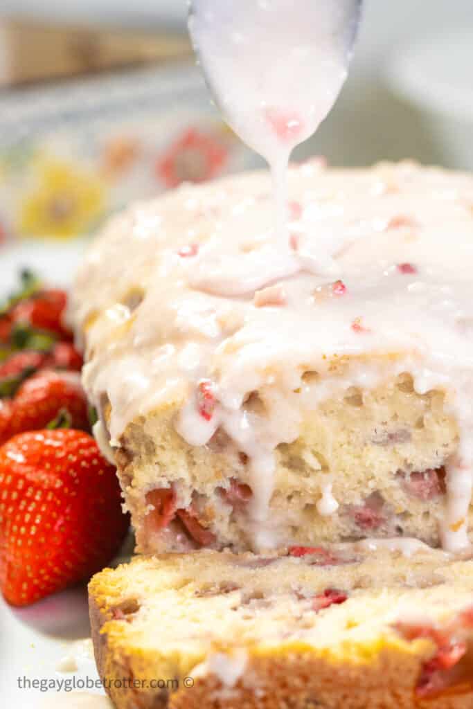 Glaze being drizzled on strawberry bread.