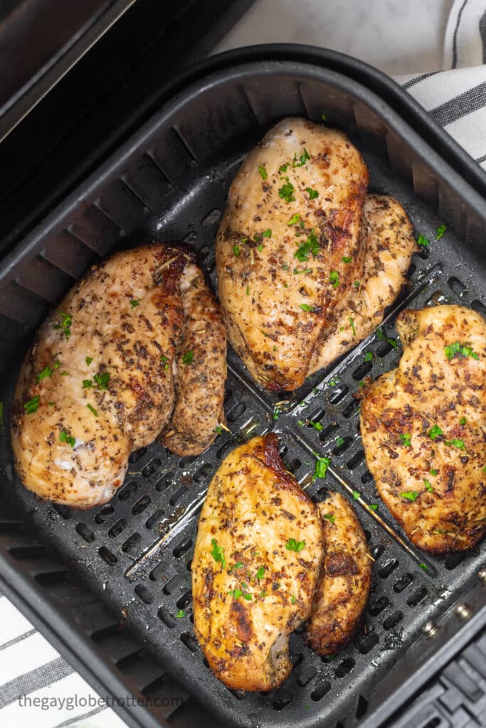 Chicken breasts being flipped in an air fryer.