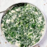 A pan of creamed spinach with a silver spoon.