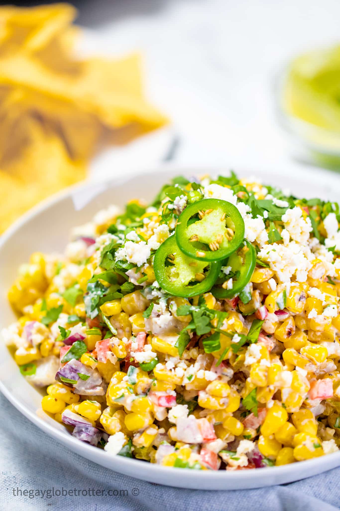 Mexican street corn on a serving plate garnished with cilantro with text overlay.