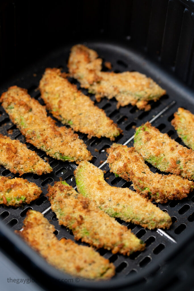 Avocado fries in an air fryer basket.