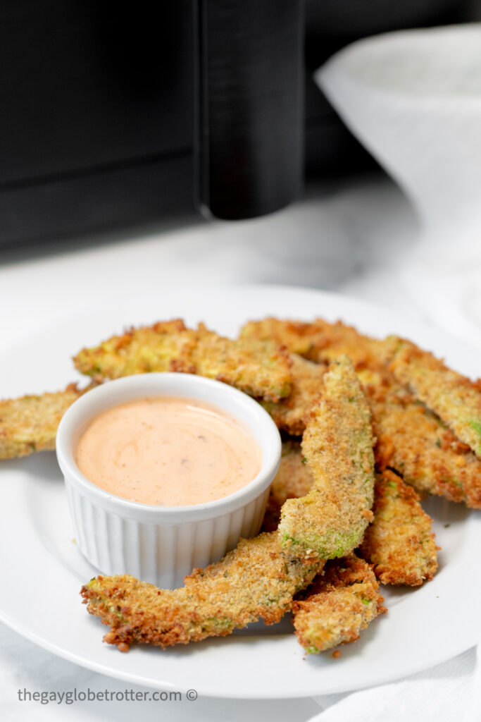 Air fryer avocado fries next to sriracha ranch dipping sauce.