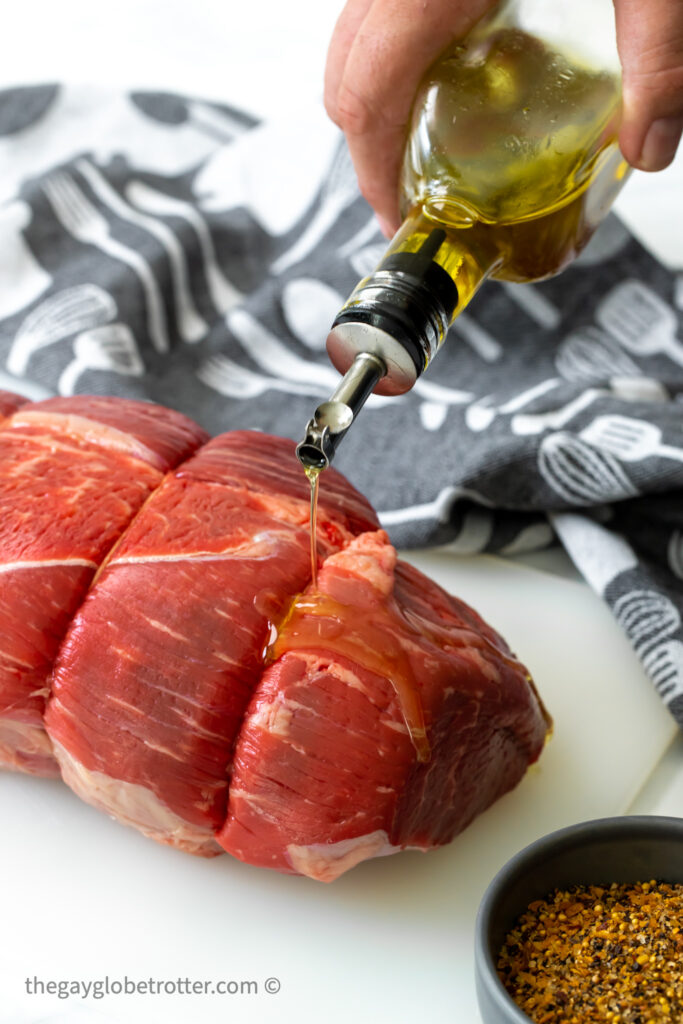 Olive oil being drizzled over a beef roast.