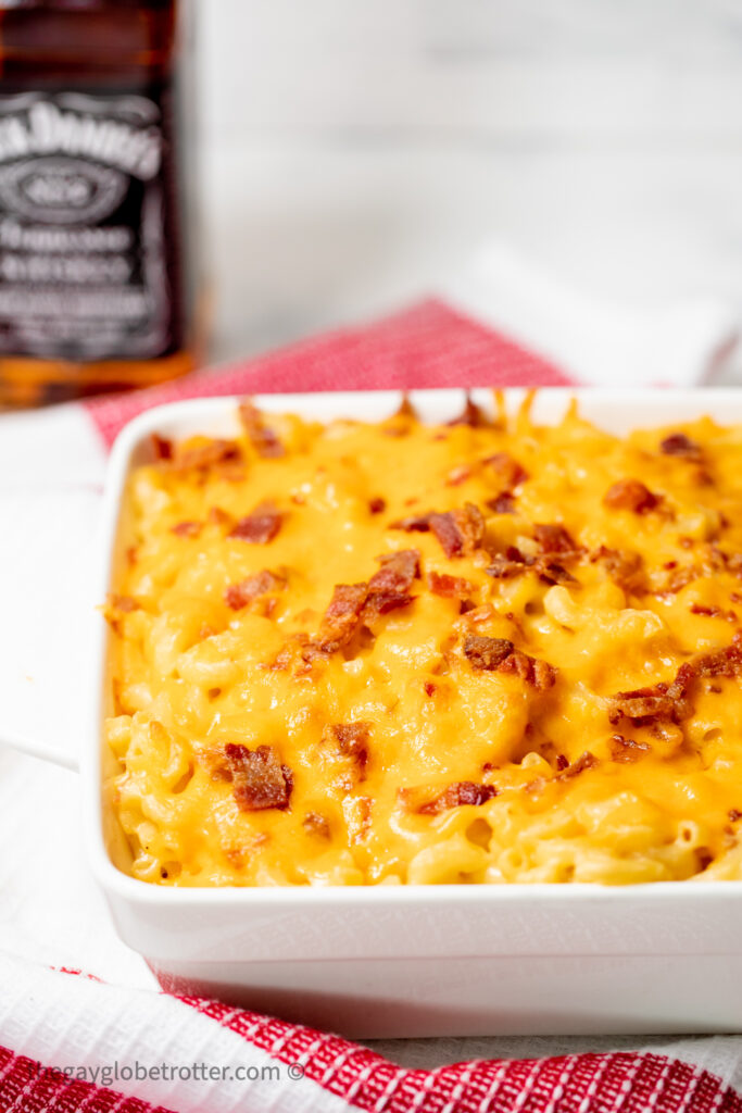 Bacon bourbon mac and cheese next to a bottle of bourbon.