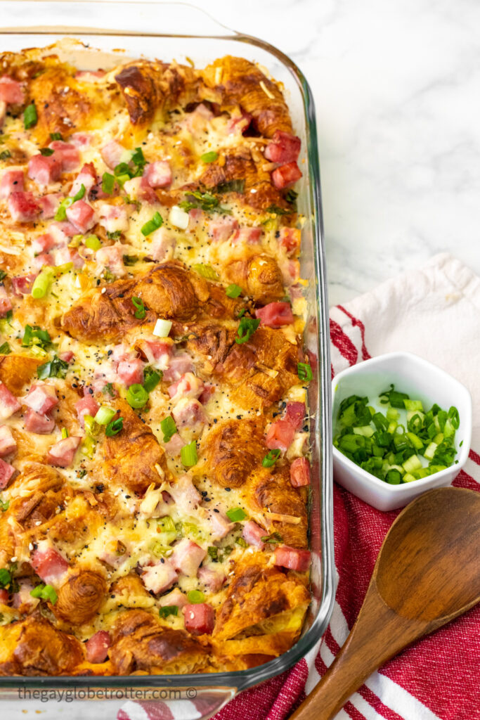 Hot ham and cheese croissant bake fresh from the oven next to green onions.