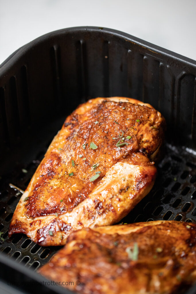 A turkey breast in the air fryer garnished with sage.