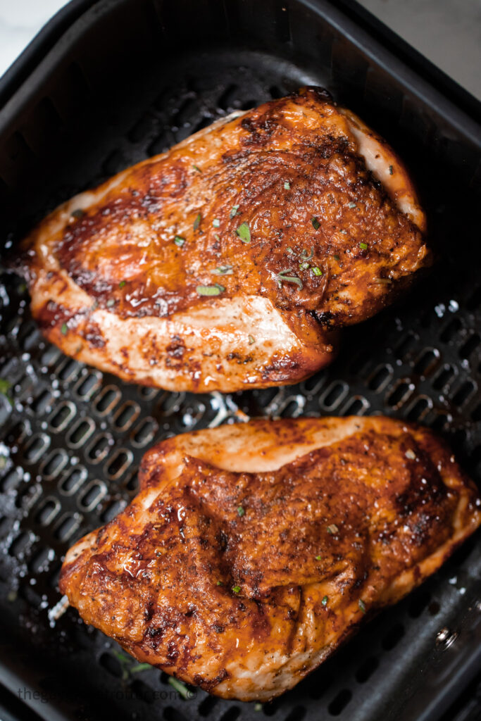 Two cooked turkey breast in an air fryer basket.