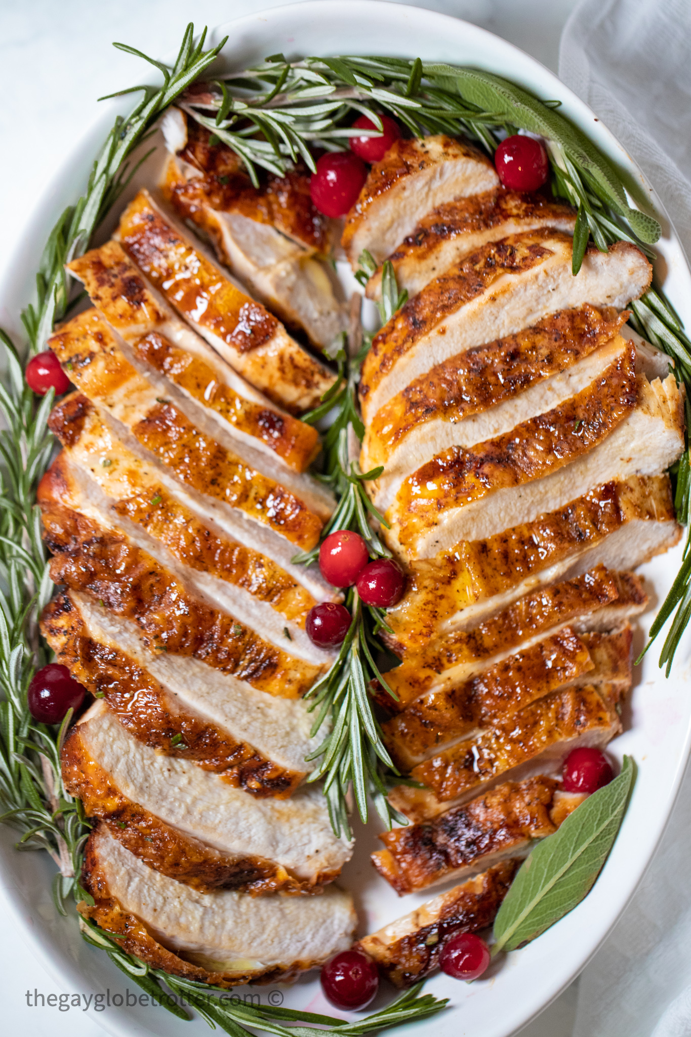 Sliced turkey breast on a serving plate garnished with rosemary.