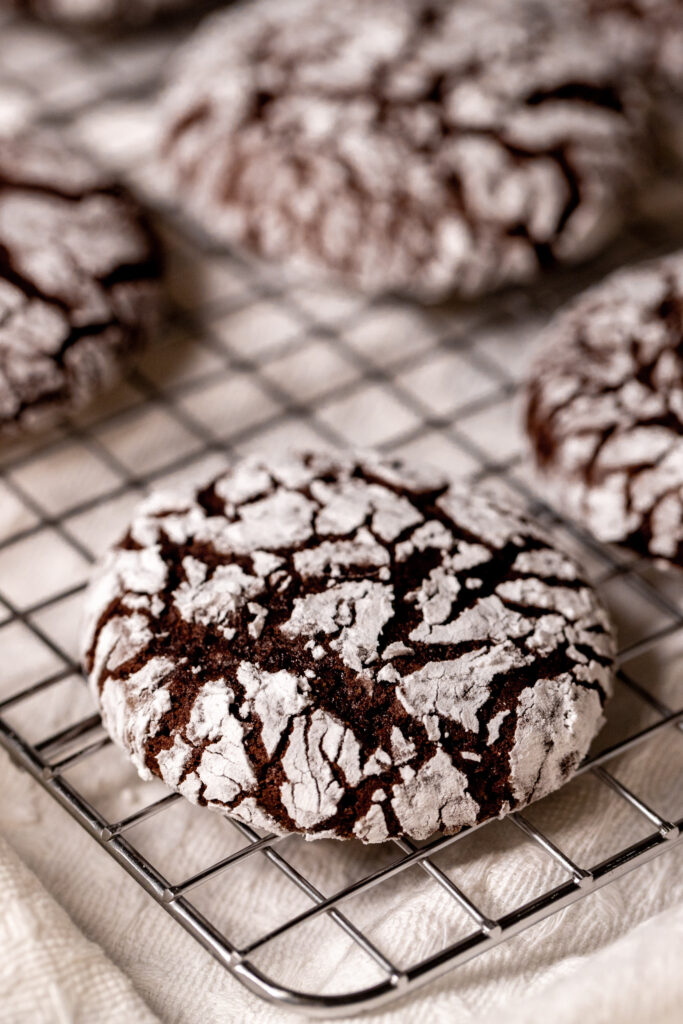 A chocolate crinkle cookie on a wire cooling rack.