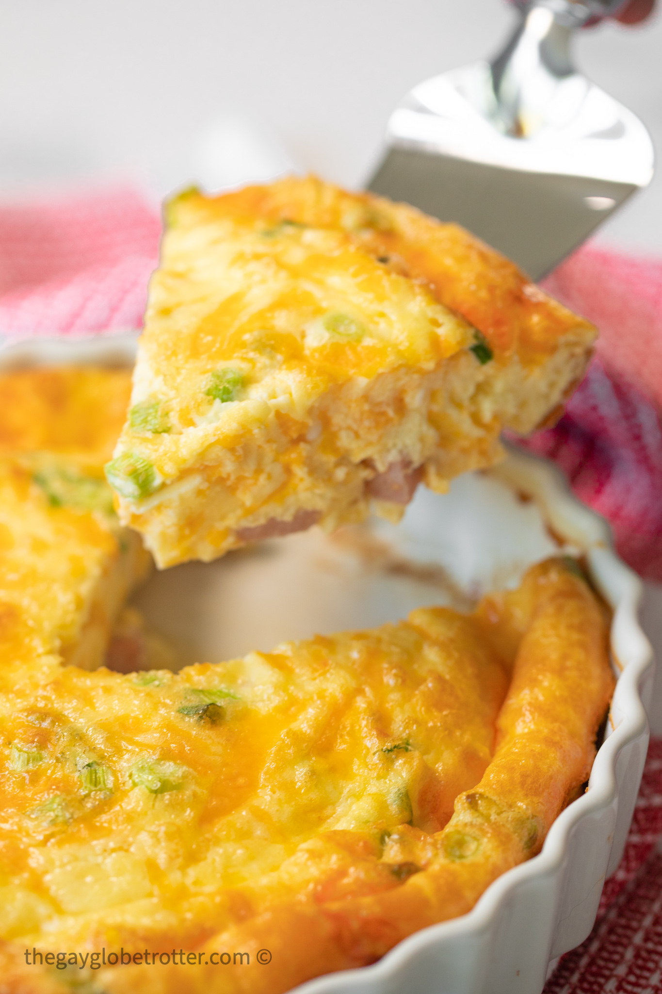 A slice of crustless ham and cheese quiche being served.