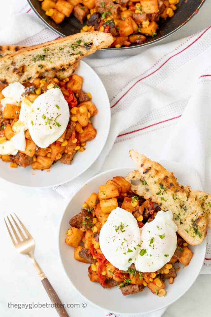 Two bowls of roast beef hash topped with poached eggs.