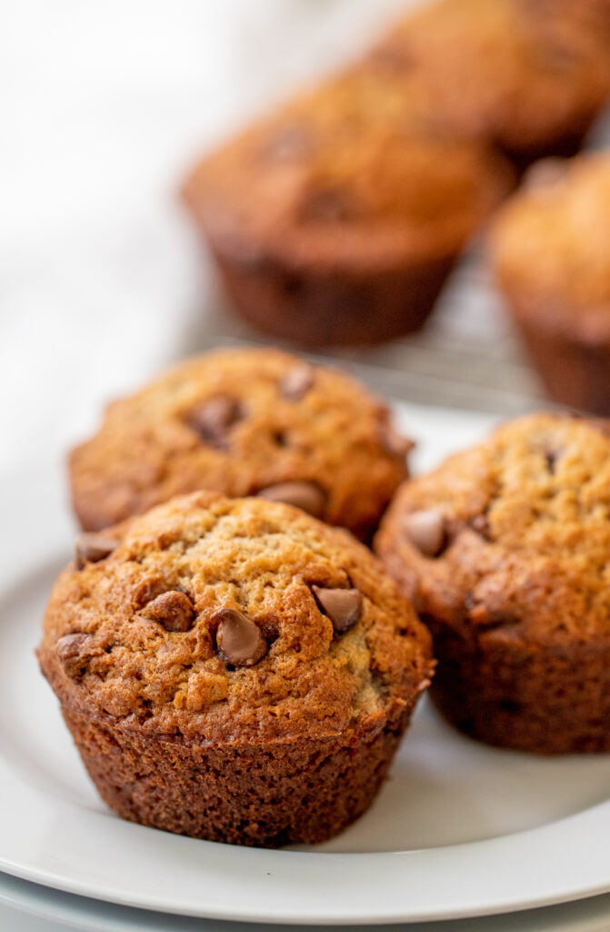 Three banana chocolate chip muffins on a plate.