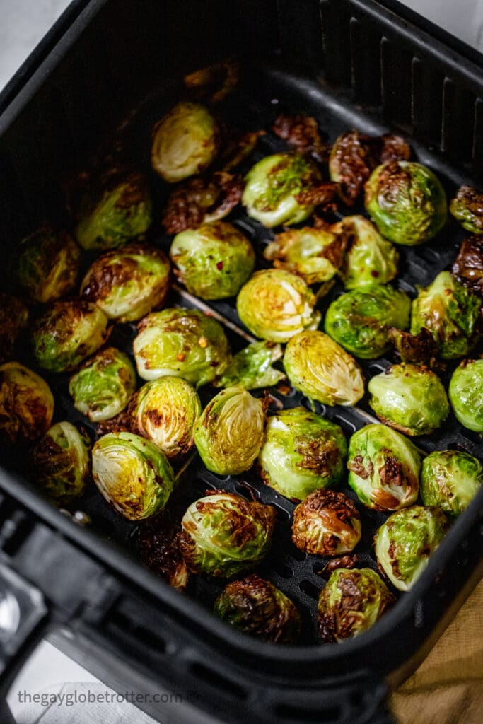 Air fryer brussels sprouts in a black air fryer basket.