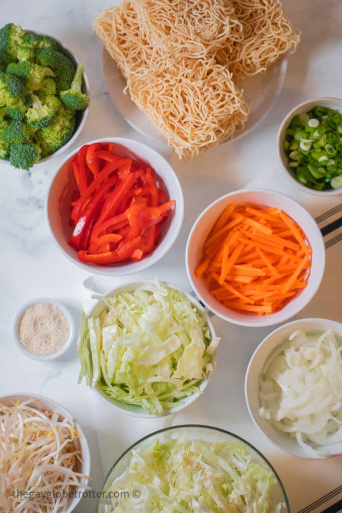 Ingredients for stir frying the lo mein next to lo mein noodles.