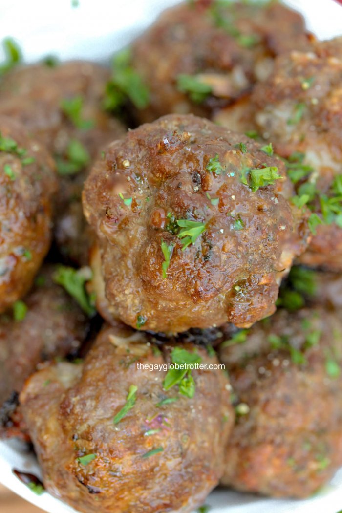 Italian meatballs piled in a serving dish garnished with parsley.