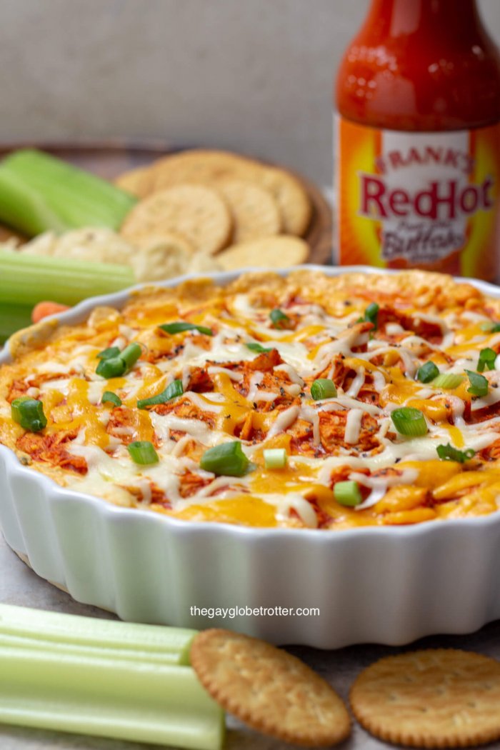 Salsa de pollo de búfalo Franks en un tazón para servir junto a apio, galletas ritz y otras cazos.