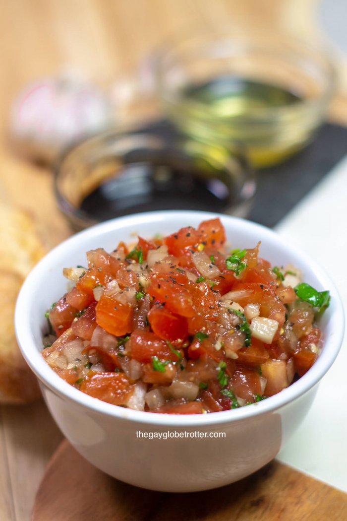 We love this easy homemade tomato bruschetta recipe. It's filled with tomatoes, onions, garlic, basil, and other delicious additions. Serve bruschetta on crostini for the perfect appetizer! #gayglobetrotter #bruschetta #tomato #tomatobruschetta #homemadebruschetta #bestbruschetta #bruschettarecipe #easybruschetta