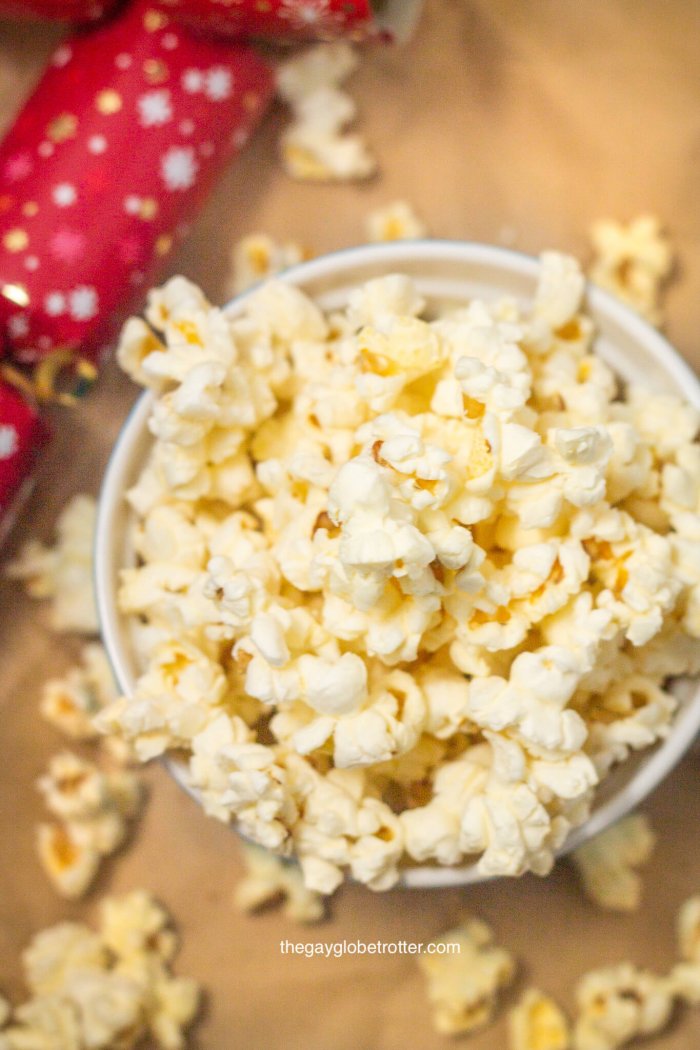 A bowl of kettle corn with a party cracker next to it.