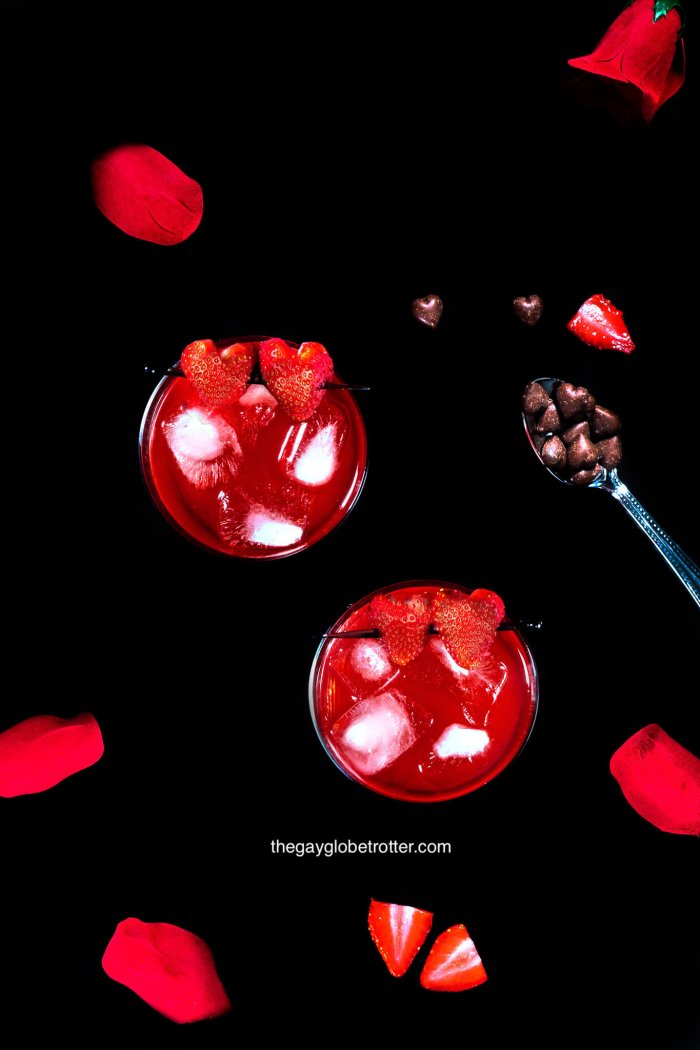 An overhead shot of love potion drinks with rose petals and chocolate hearts.