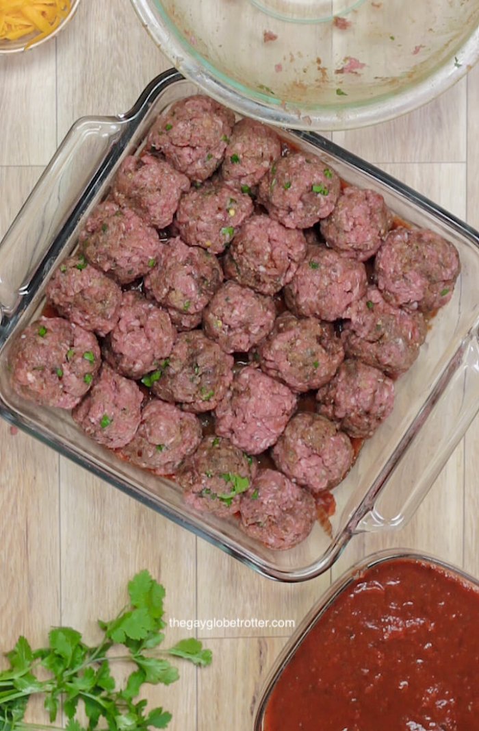 Taco meatball casserole being assembled in a baking dish.